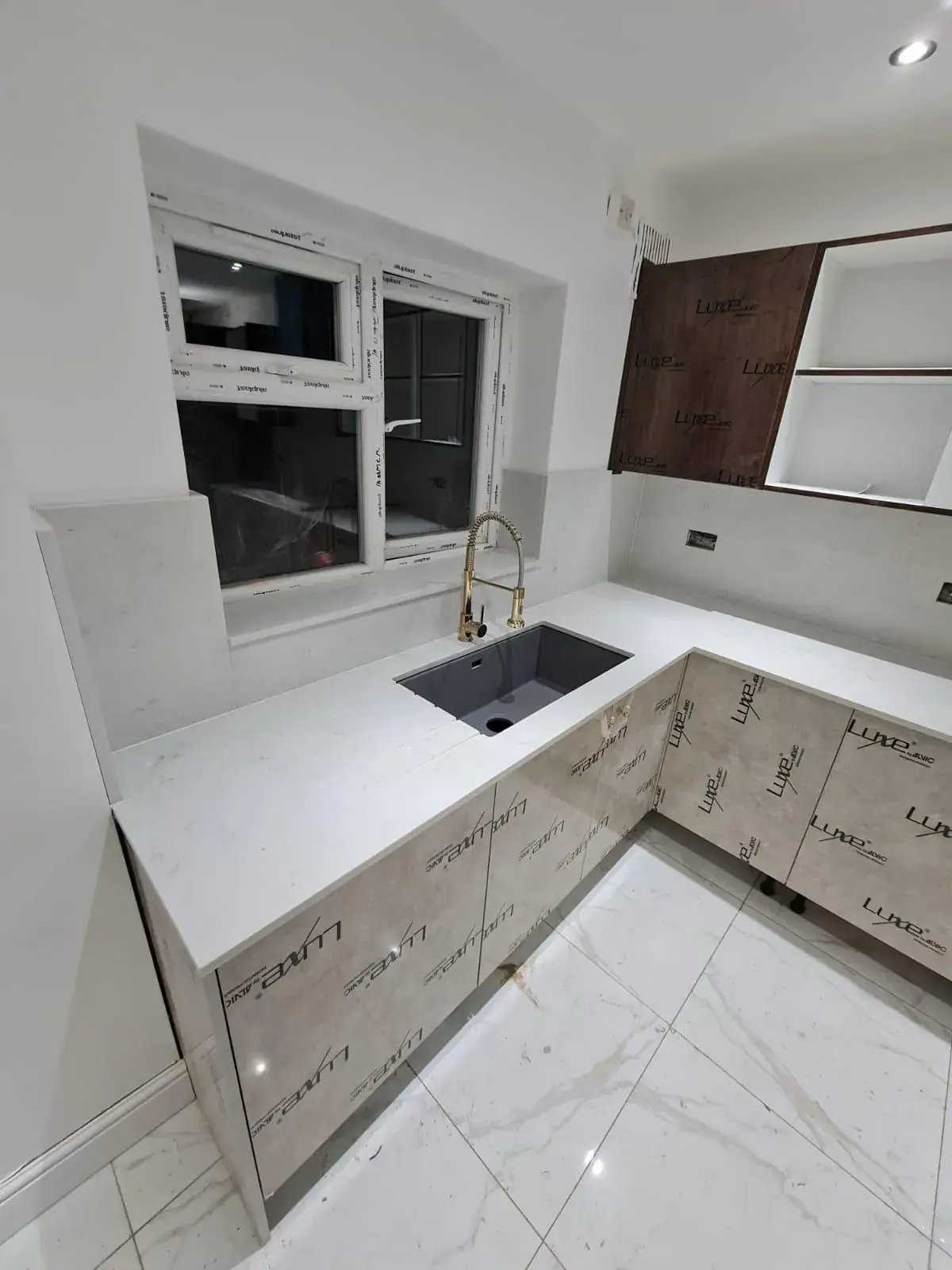 Kitchen sink area with gold tap fixture and marble countertop